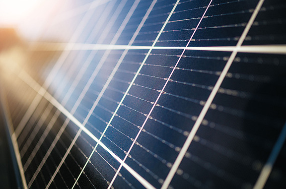 Close-up of solar cells on a photovoltaic module that converts sunlight into electrical energy. The shiny surface shows the fine lines of the solar cells, a symbol of sustainable power generation and climate protection.