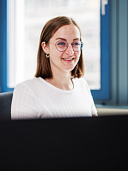 Larina, Auszubildende Bauzeichnerin bei der Zentralen Technik, sitzt an ihrem Schreibtisch.