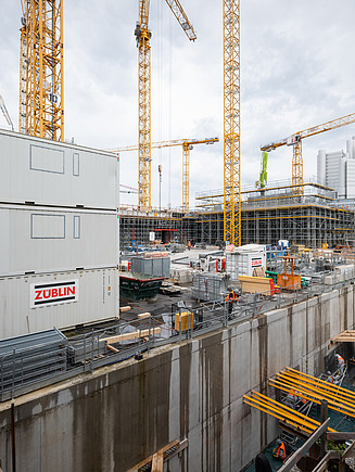 Im Vordergrund sind Baucontainer von ZÜBLIN zu sehen, im Hintergrund die ersten Geschosse des TRIDEA.