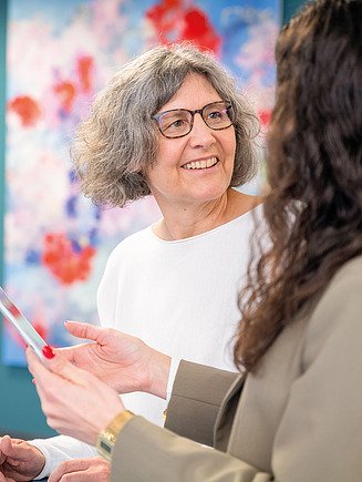 Eine erfahrene Ingenieurin steht an einem Stehtisch und bespricht die Planung digitaler Baumodelle.