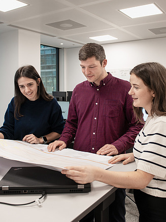 An apprentice discusses design plans with her colleagues.