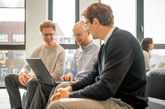Personen sitzen zusammen und besprechen ein Projekt am Laptop – Fokus auf Zirkuläres Bauen und nachhaltige Planung