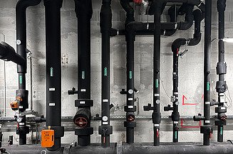The picture shows large black pipes as part of the technical building equipment in the Althan Quartier.