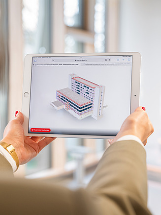 Eine Frau hält auf dem Bild ein Tablet in den Händen, auf dem ein BIM-Modell gezeigt wird - ein perfektes Beispiel für Smart Engineering in der digitalen Planung