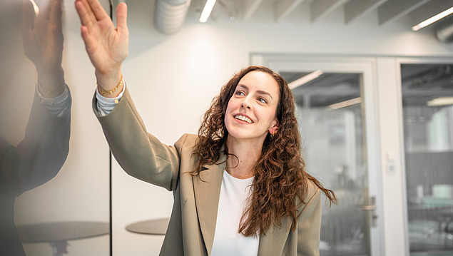 The picture shows an employee of the central technology department pointing at a large screen.