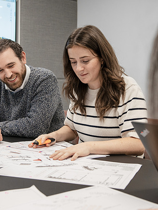 Eine Auszubildende bespricht Pläne in einem Meeting mit ihrem Team.