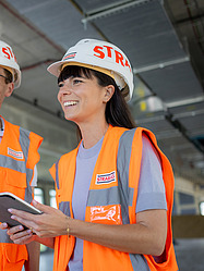 Saskia, Architektin bei der Zentralen Technik, steht mit einem Arbeitskollegen auf der Baustelle.