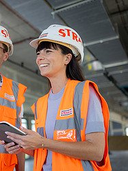 Saskia, Architektin bei der Zentralen Technik, steht mit einem Arbeitskollegen auf der Baustelle.