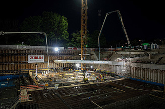 The challenging excavation pit in the dark and floodlit by the construction spotlights.