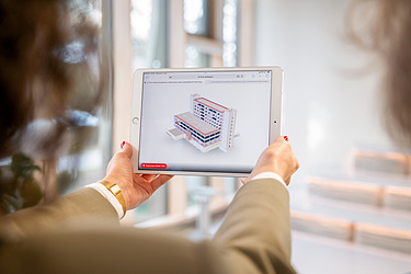 Das Bild zeigt eine menschliche Hand, die ein Tablet mit einem Modell drauf hält.