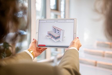 The picture shows a human hand holding a tablet with a model on it.