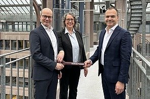 Markus Landgraf übergibt den symbolischen Staffelstab an Sabine Hahn und Niels Dürr - das neue Führungskräfteduo der Zentralen Technik.