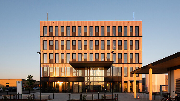 Das nachhaltige Büro T3 von ZÜBLIN Timber wird vom Sonnenaufgang in Aichach angeleuchtet.