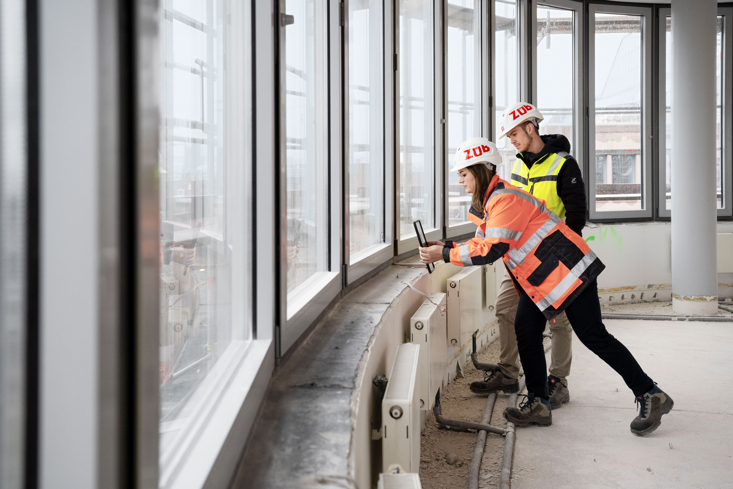 Das Bild zeigt zwei Personen mit einem Tablet in einer Baustellenumgebung - Building Information Management