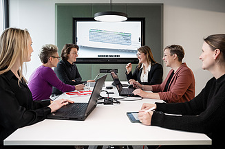 The image shows a BIM model and BIM experts in a meeting.