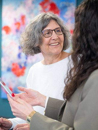 Eine erfahrene Ingenieurin steht an einem Stehtisch und bespricht die Planung digitaler Baumodelle.