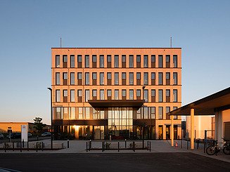 Das nachhaltige Büro T3 von ZÜBLIN Timber wird vom Sonnenaufgang in Aichach angeleuchtet.