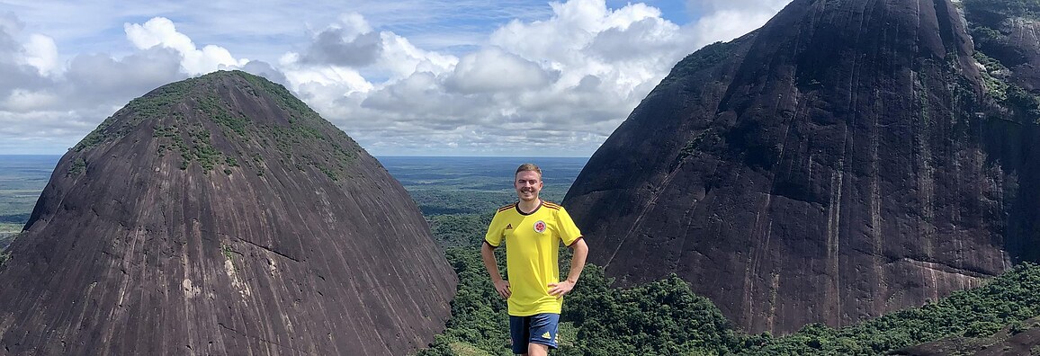Ein ehemaliger Trainee steht während seines Auslandseinsatzes in Kolumbien in einem kolumbianischen Fußballtrikot in den kolumbianischen Bergen.