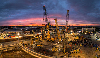 Das Bild zeigt riesige Baukräne des HS2-Tunnelbau-Projektes im Sonnenuntergang von London.
