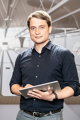 Ambrosius, BIM-Manager bei der Zentralen Technik, steht vor einer Visualisierung des neuen Stuttgarter Hauptbahnhofs.