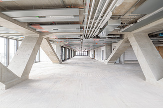 Das Bild zeigt eine Etage im fertiggestellten Rohbauzustand, inklusive der abgeschlossenen Installation aller TGA-Anlagen.                          
