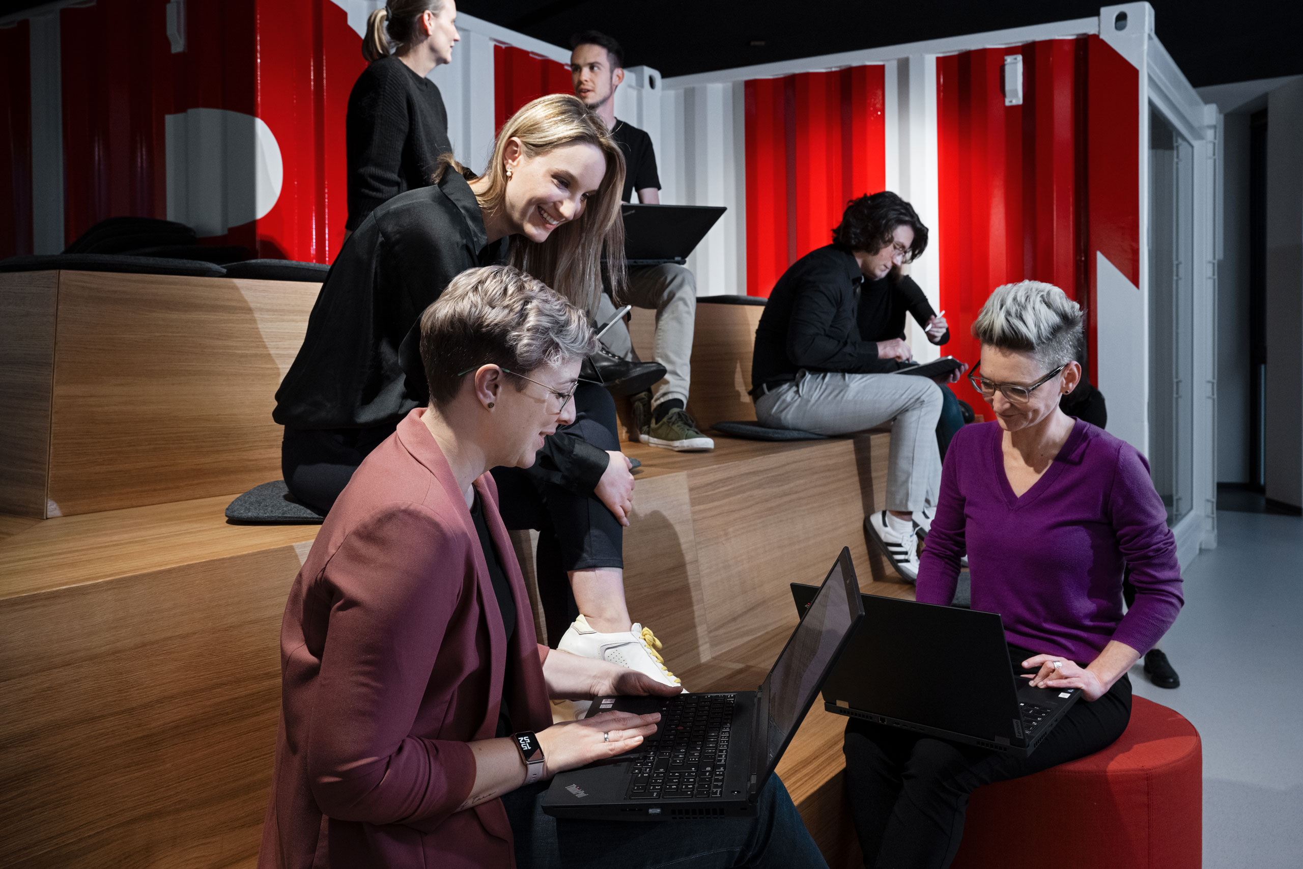 The picture shows several people with laptops on steps