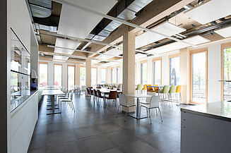 Die Stühle und Tische in der Kantine von ZÜBLIN Timber werden durch das Tageslicht hell erleuchtet.