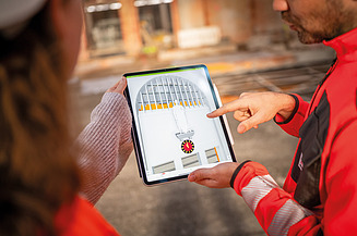 Planen und Bauen aus einer Hand: Zwei Personen betrachten ein digitales Modell der Baustelle auf einem Tablet