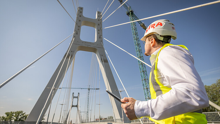 The picture shows a civil engineer and a bridge pylon of the Satu Mare Bridge