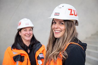 Zwei berufserfahrene Ingenieurinnen stehen auf der Stuttgart-21-Baustelle und lächeln in die Kamera.