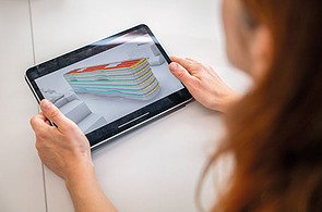 Das Bild zeigt eine Frau, die das digitale Modell des Gebäudes Z2 begutachtet. Zu sehen sind Nachhaltigkeitsbetrachtungen.