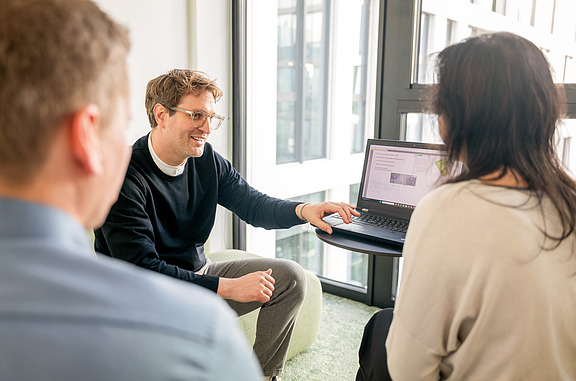 Meeting on sustainability consulting with a laptop in a modern office with large windows.