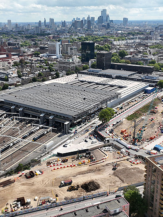 The picture shows a construction project, more precisely a train station with many tracks and a city around it