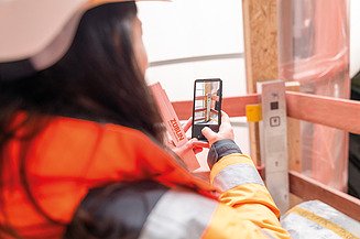 Planning and execution on the construction site: architect documents construction progress with her smartphone.
